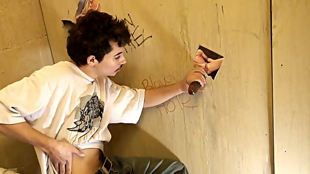Weird dude is sucking a black cock in a gloryhole
