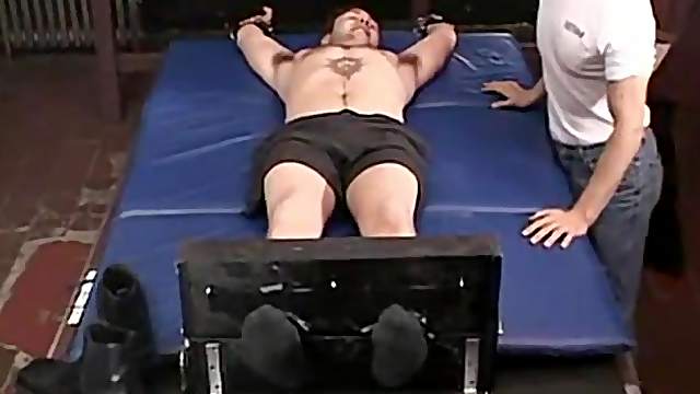 Two older guys having fun tickling a tied up  dude