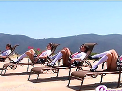 Four beautiful ladies in plaid skirts and knee high socks tan outdoors