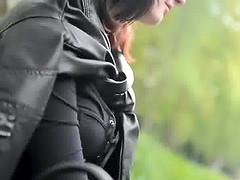 Prostitute in leather clothes smokes while waiting for clients